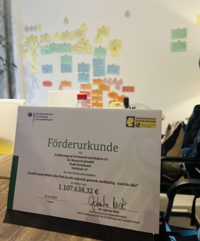 Förderurkunde vor einem Hintergrund mit Moderationskarten
